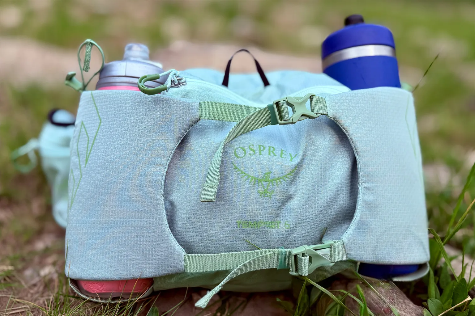 Osprey Tempest 6 腰包特写,展示了其标志、扣环和双水壶袋。 Osprey Tempest 6 腰包特写,展示了其标志、扣环和双水壶袋。